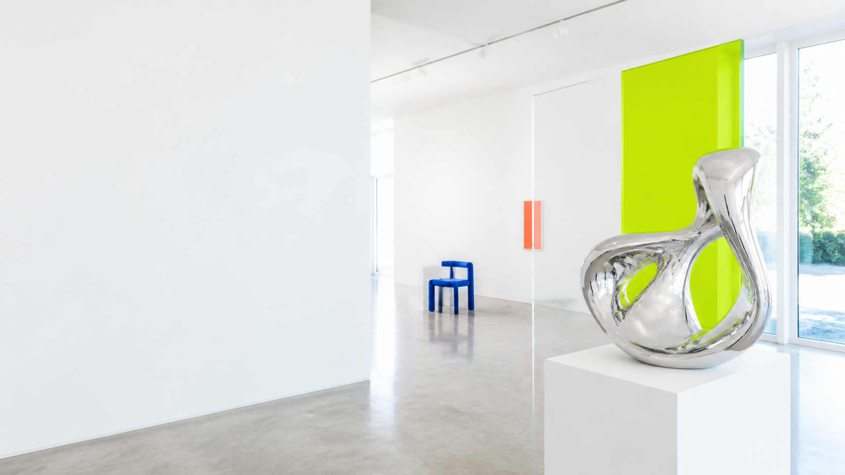 Bright gallery-like studio with chrome sculpture and lime acrylic panel